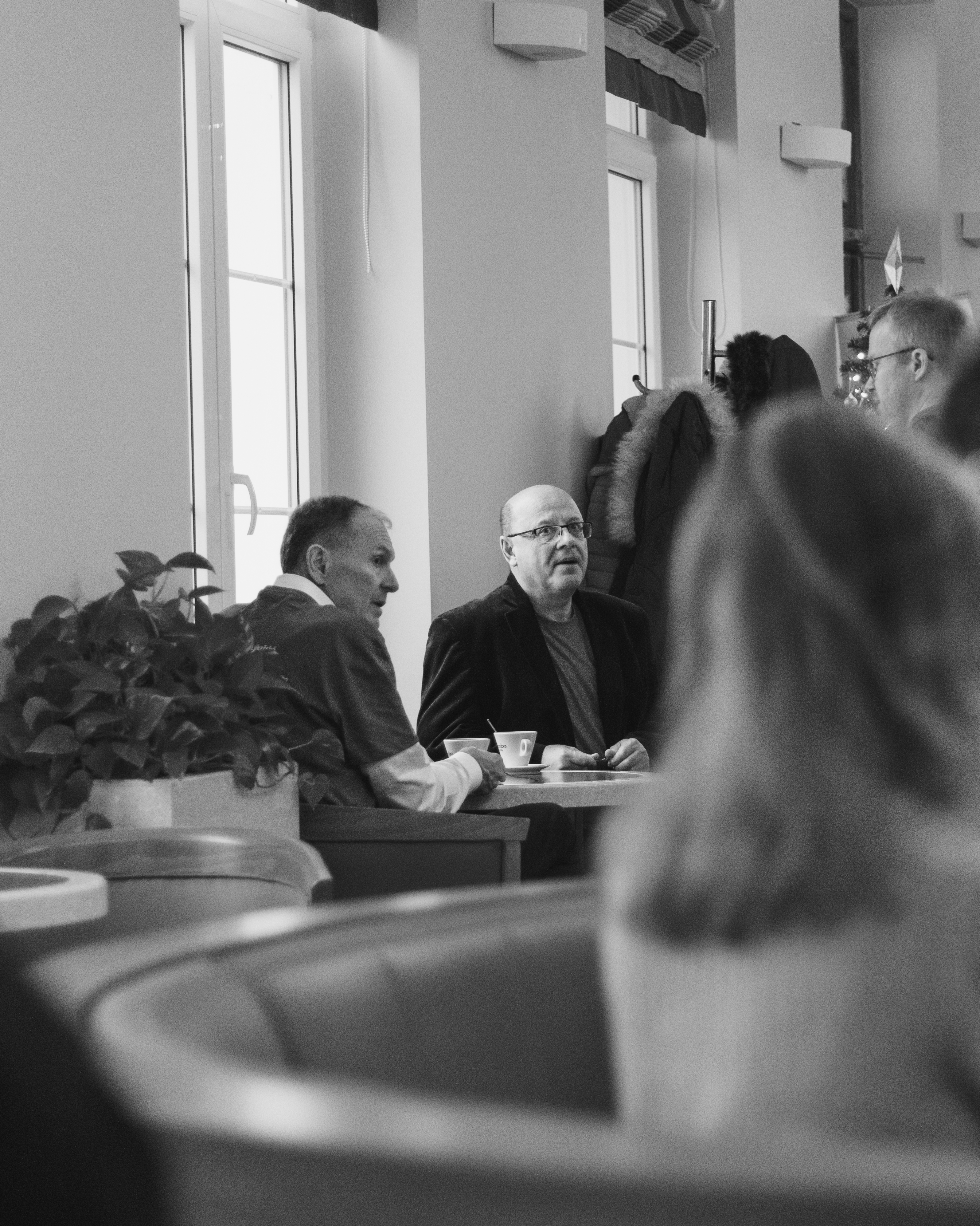 Přednášející v crocs, celá postava na pódiu, černo-bílá fotografie